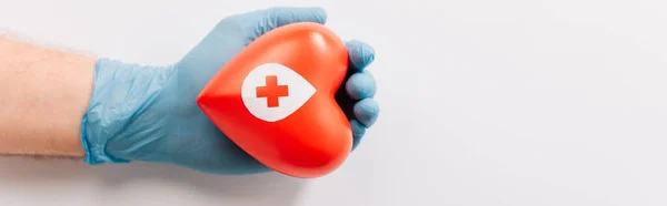 Cropped view of male hand in latex glove with red heart on white, blood donation concept — Stock Photo