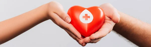 Обрізаний вид чоловіка і жінок, що тримають червоне серце ізольовано на білому фоні, концепція донорства крові — стокове фото