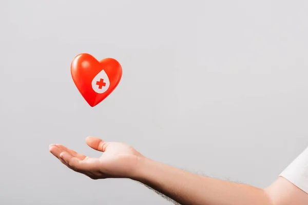 Обрізаний вид чоловічої руки і червоне серце ізольовано на білому фоні, концепція донорства крові — стокове фото