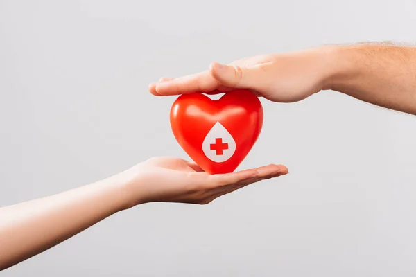 Vista recortada de hombres y mujeres con corazón rojo aislado en blanco, concepto de donación de sangre - foto de stock