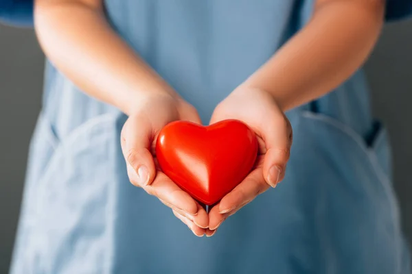 Vista recortada del médico sosteniendo el corazón rojo - foto de stock