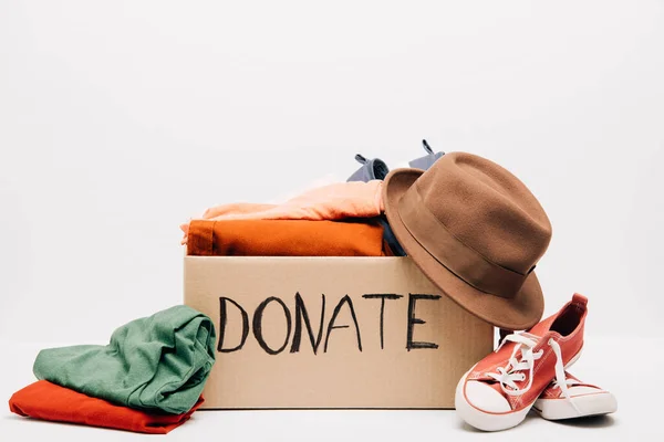 Boîte en carton avec des vêtements donnés et des chaussures isolées sur blanc, concept de charité — Stock Photo