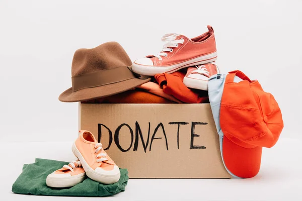 Caja de cartón con accesorios donados, ropa y calzado aislado en blanco, concepto de caridad - foto de stock