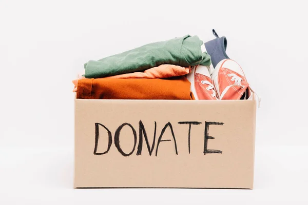 Cardboard box with donated clothes and footwear isolated on white, charity concept — Stock Photo