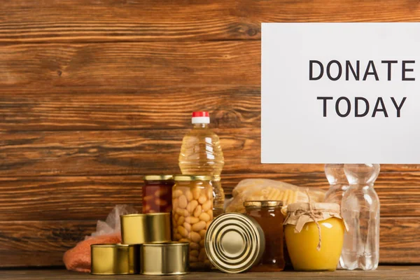 Donate today card near food on wooden background, charity concept — Stock Photo