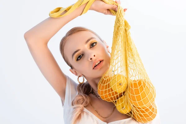 Mulher na moda posando com frutas cítricas em saco de cordas isolado no branco — Fotografia de Stock