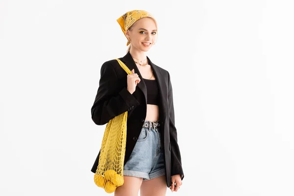 Donna alla moda in posa con limoni in borsa stringa isolato su bianco — Foto stock