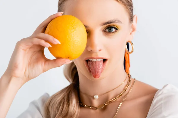 Rubia mujer mostrando lengua mientras posando con naranja aislado en blanco - foto de stock