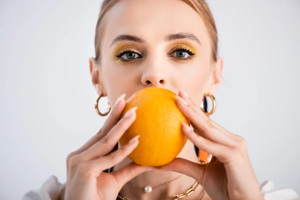 Elegante blonde Frau posiert mit Orange auf der Vorderseite des Gesichts isoliert auf weiß — Stockfoto