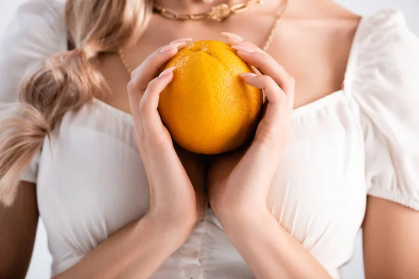 Vista recortada de mujer rubia elegante sosteniendo naranja - foto de stock