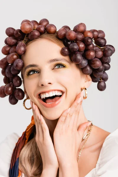 Mujer rubia rústica con uvas en la cabeza riendo aislado en blanco - foto de stock