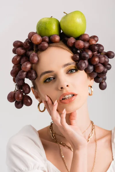 Retrato de mujer rubia rústica posando con uvas y manzanas en la cabeza aislada en blanco - foto de stock
