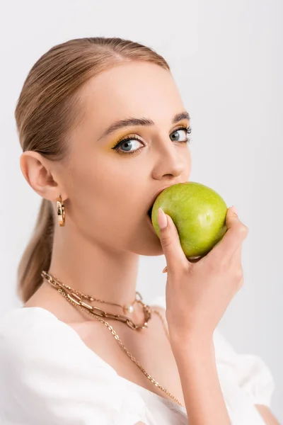 Mulher loira mordendo maçã verde isolado no branco — Fotografia de Stock