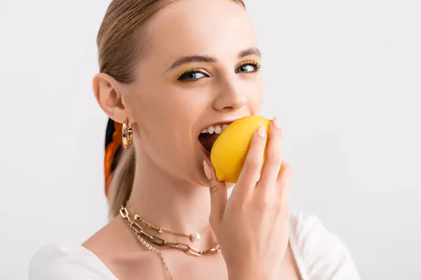 Mujer rubia rústica mordiendo limón amarillo aislado en blanco - foto de stock