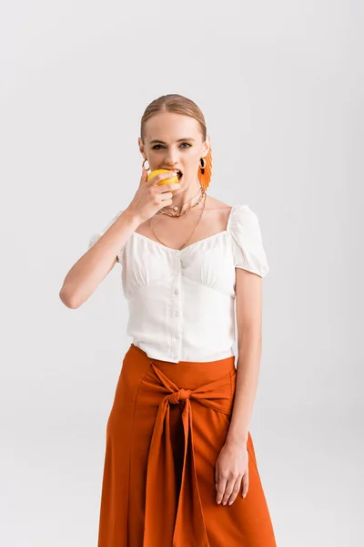 Mujer rubia rústica mordiendo limón amarillo aislado en blanco - foto de stock