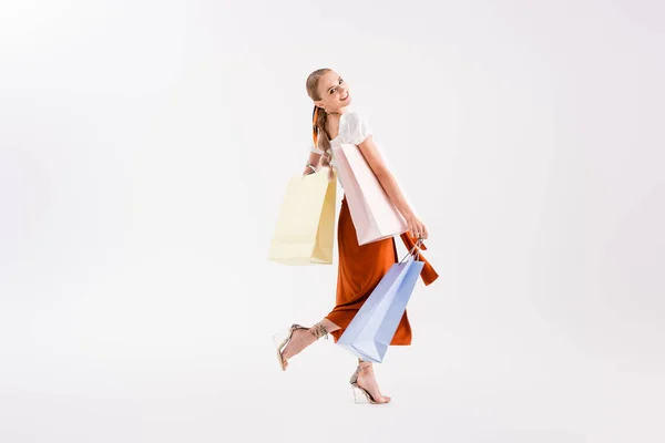 Vista completa de la mujer elegante caminando con bolsas de compras en blanco - foto de stock