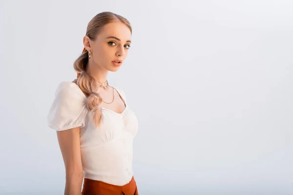Elegante blonde Frau in weißer Bluse, die isoliert auf weißer Bluse in die Kamera blickt — Stockfoto