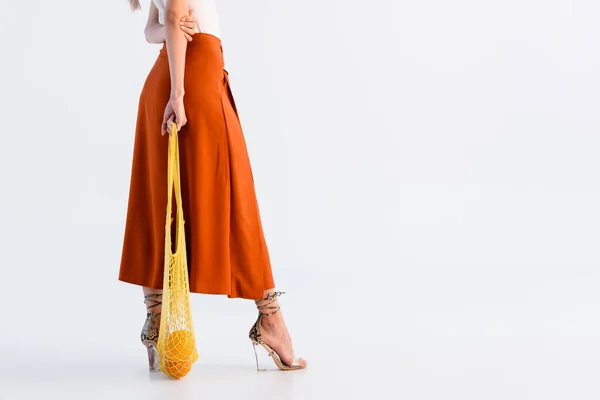 Vista cortada da mulher na saia posando com frutas cítricas em saco de corda amarela isolado no branco — Fotografia de Stock