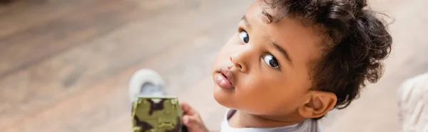 Imagem horizontal do menino americano africano olhando para a câmera enquanto segurando brinquedo, vista aérea — Fotografia de Stock