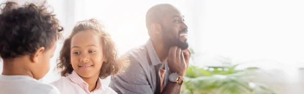 Plan panoramique de l'homme afro-américain excité près de sa fille et de son fils à la maison — Photo de stock