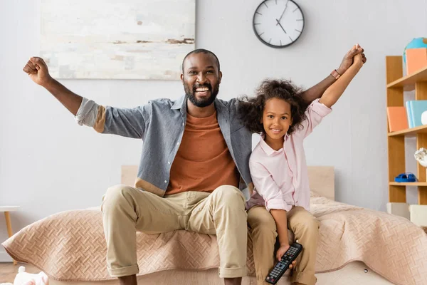 Excited african american man with daughter showing winner gesture while looking at camera — Stock Photo