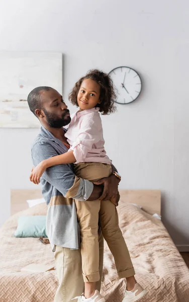 Junger afrikanisch-amerikanischer Vater hält Tochter an Händen, während sie in die Kamera schaut — Stockfoto