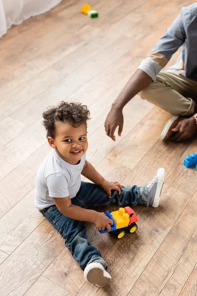 Cropped view of african american man near son playing with toy truck on floor — Stock Photo