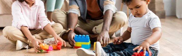Ausgeschnittene Ansicht eines afrikanisch-amerikanischen Vaters mit Kindern, die mit Bauklötzen auf dem Boden spielen, Panoramaaufnahme — Stockfoto