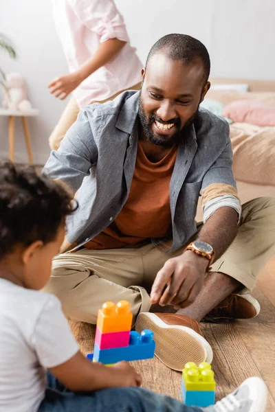 High angle view of young african american father sitting on floor near son playing with building blocks — Stock Photo
