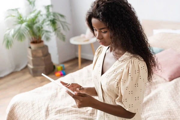 Hochwinkelaufnahme einer fokussierten afrikanisch-amerikanischen Frau, die zu Hause ein digitales Tablet benutzt — Stockfoto