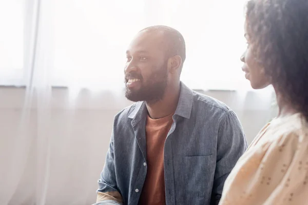 Selective focus of african american wife looking at excited husband at home — Stock Photo