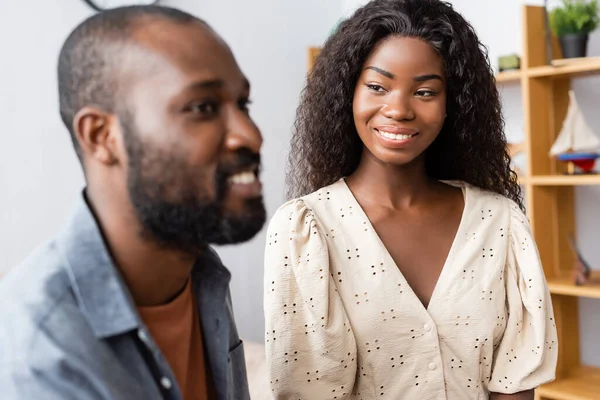 Selective focus of african american woman in blouse looking at husband at home — Stock Photo