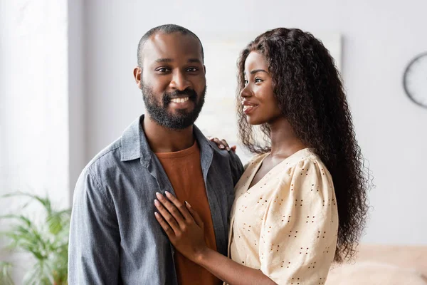 Jovem afro-americana tocando marido olhando para a câmera em casa — Fotografia de Stock