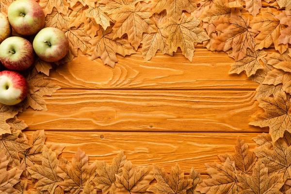 Верхний вид спелых яблок и осенней листвы на деревянном фоне — стоковое фото