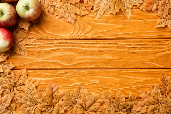 Top view of ripe apples and autumnal foliage on wooden background — Stock Photo