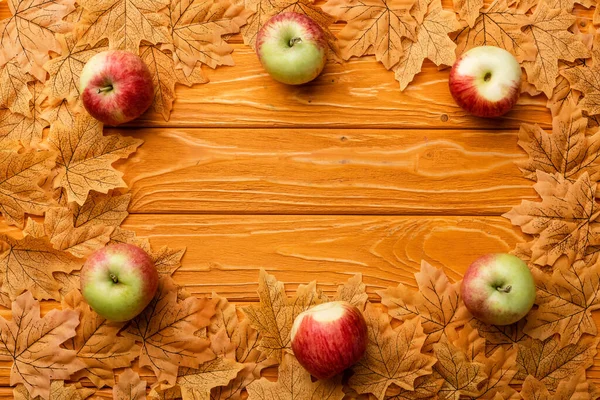 Vista superior de manzanas maduras y follaje otoñal sobre fondo de madera - foto de stock