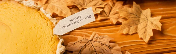 Thanksgiving pumpkin pie with autumnal foliage on wooden background, panoramic shot — Stock Photo