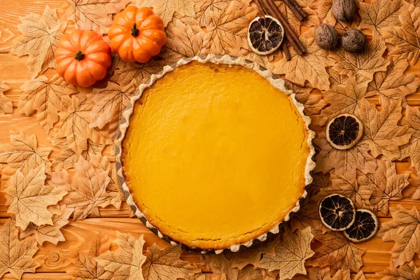 Top view of pumpkin pie with autumnal decoration on wooden background — Stock Photo