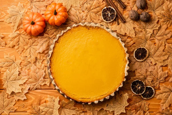 Vista dall'alto della torta di zucca con decorazione autunnale su sfondo di legno — Foto stock