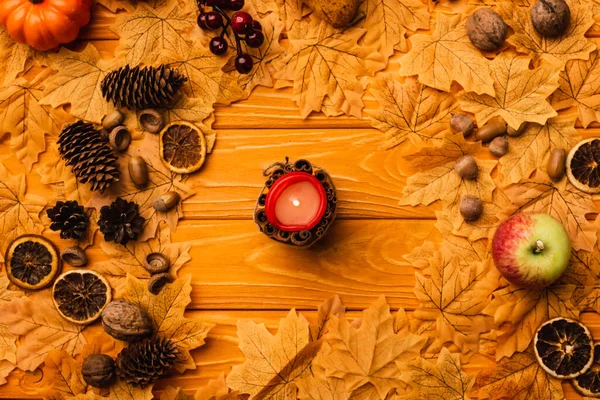 Draufsicht auf brennende Kerze mit herbstlicher Dekoration auf Holzgrund — Stockfoto