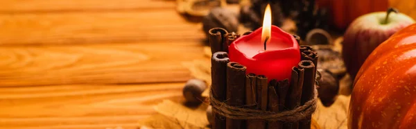 Selective focus of burning candle with autumnal decoration on wooden background, panoramic shot — Stock Photo