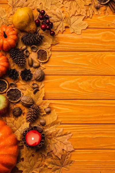 Draufsicht auf brennende Kerze mit herbstlicher Dekoration auf Holzgrund — Stockfoto