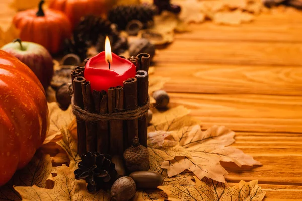 Selective focus of burning candle with autumnal decoration on wooden background — Stock Photo