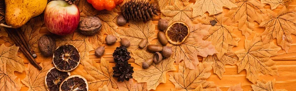 Top view of autumnal decoration and food on golden foliage on wooden background, panoramic shot — Stock Photo