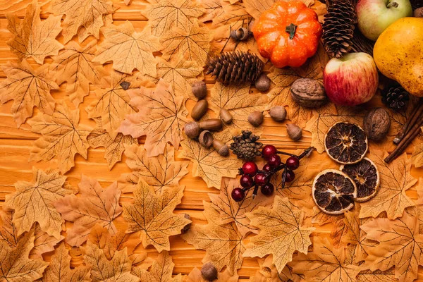 Draufsicht auf herbstliche Dekoration und Lebensmittel auf goldenem Laub auf hölzernem Hintergrund — Stockfoto