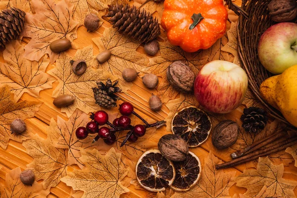 Ansicht der herbstlichen Dekoration und Lebensmittel aus Weidenkorb auf goldenem Laub auf hölzernem Hintergrund verstreut — Stockfoto