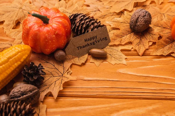 Milho, abóbora, decoração outonal e cartão de ação de graças feliz no fundo de madeira — Fotografia de Stock