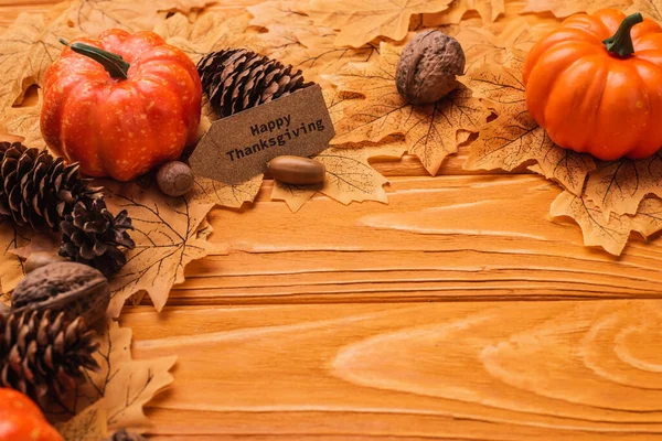 Calabazas, decoración otoñal y feliz tarjeta de acción de gracias sobre fondo de madera - foto de stock