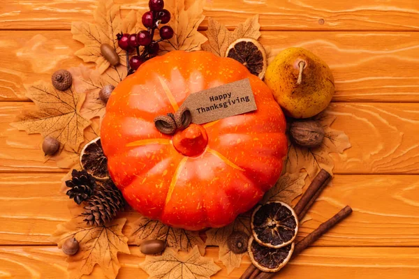 Vista superior de la calabaza con decoración otoñal y feliz tarjeta de acción de gracias sobre fondo de madera - foto de stock