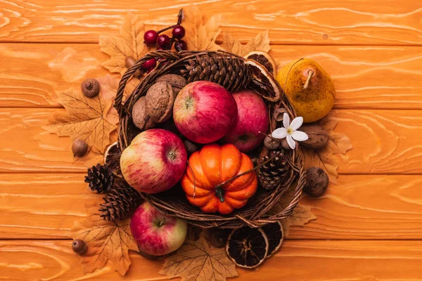 Top view of wicker basket with autumnal harvest on wooden background — Stock Photo